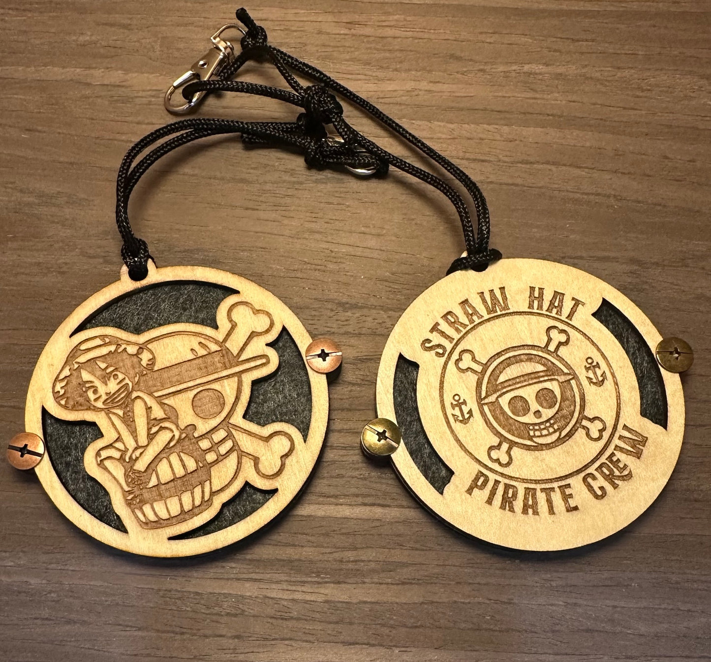 Two laser cut basswood essential oil car fresheners with Straw Hat Pirate Crew engraved designs and felt backing